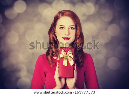 Redhead women with gift. Photo with bokeh at background.