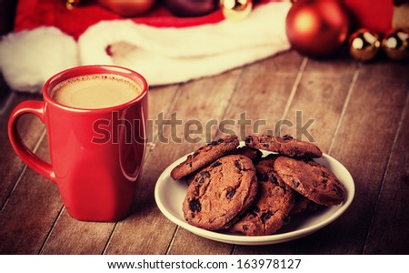 Cookies and cup of coffee with christmas gifts at background