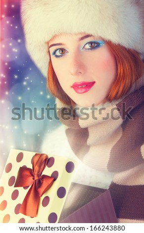 Beautiful redhead women with gift. Photo with bokeh at background.