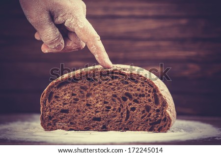 Baker\'s hands with a bread. Photo with high contrast