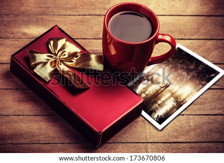 Gift, photo and cup of coffee on wooden table