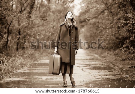 Style girl with suitcase at beautiful autumn alley. Photo in old color image style.