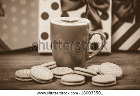 Cookies and cup of coffee with gifts at background