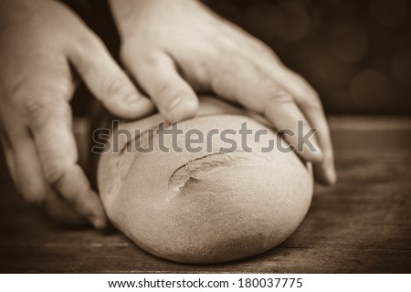 Baker's hands with a bread. Photo with high contrast