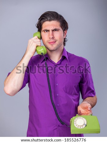Handsome man with telephone on gray background.