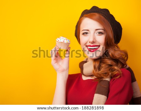 Redhead girl with cake on yellow background.
