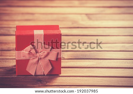 Red gift box on wooden table. Photo in retro color image style.