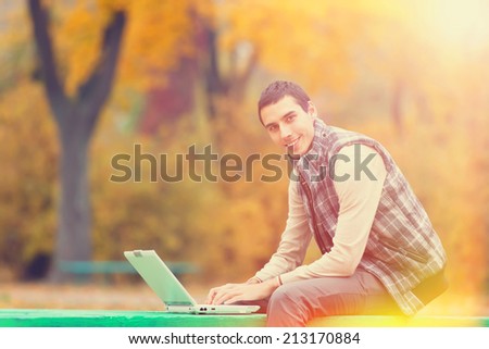 Programmer with notebook sitting in autumn park