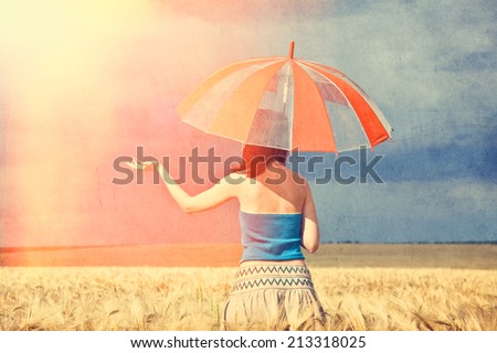 Redhead girl with umbrella at field