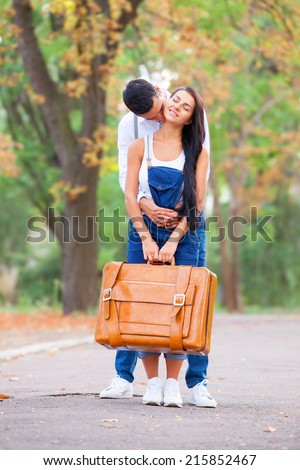 Teen couple with retro suitcase in the park in autumn time