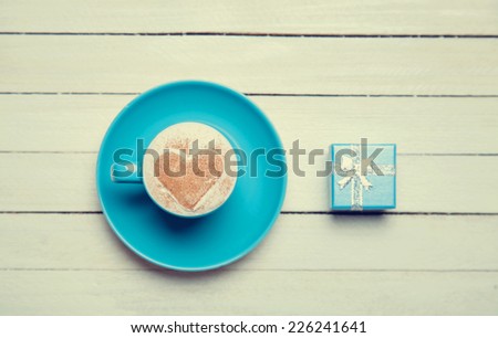 Cup of coffee and gift on wooden table.