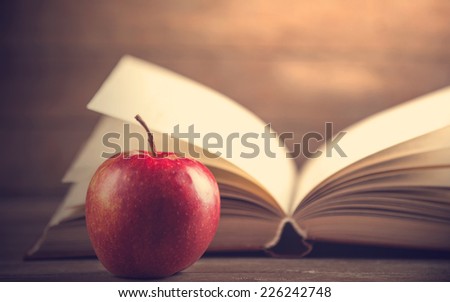 Red apple and book on a table.