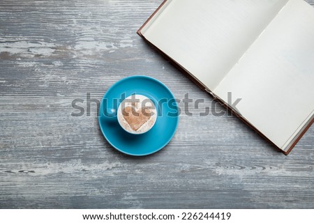 Book and cup of coffee on wooden table.