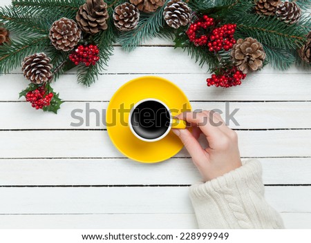 Girl holding cup of coffee near Pine branches