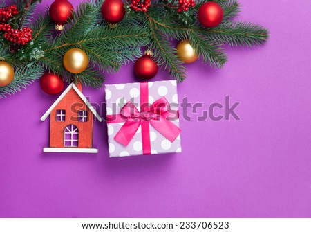 Toy house and pine branches with gift on blue background.