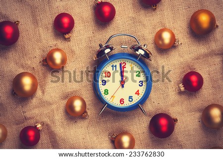 Retro alarm clock with gold and red balls on jute background.