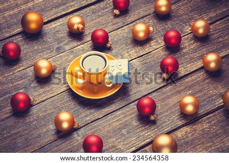 Cup of coffee and christmas balls and gift on wooden table.