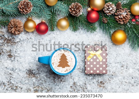 Cappuccino with christmas tree shape and gift box on artificial snow