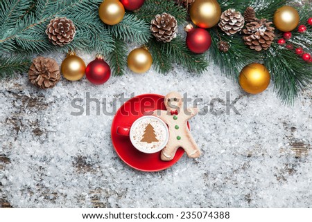 Cappuccino with christmas tree shape and gingerbread man on artificial snow background