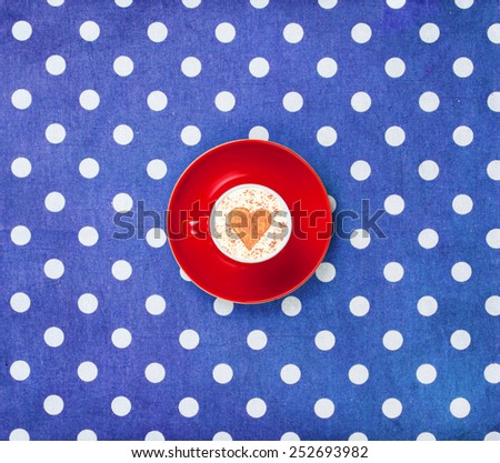 Cup of coffee with heart shape symbol on polka dot background