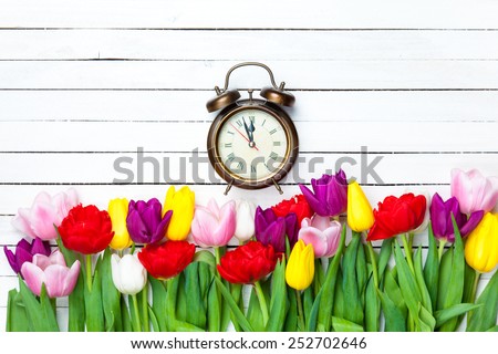 Alarm clock and tulips on white background