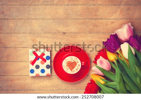 Cup of Cappuccino with heart shape symbol and gift box on wooden background
