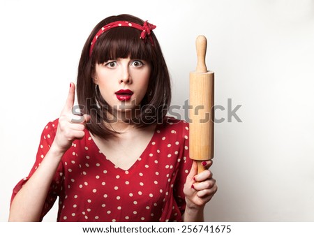 Portrait of a housewife red dress with rolling pin on white background.