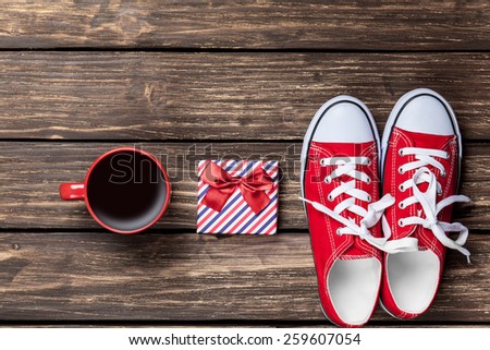 gumshoes and cup of coffee with gift on a wooden background