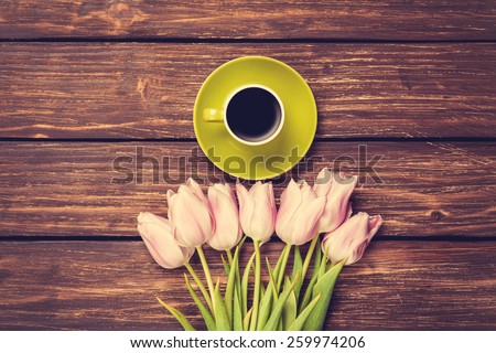 Cup of coffee and bouquet of tulips on a wooden background