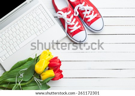 White computer and bouquet of tulips with gumshoes on white background