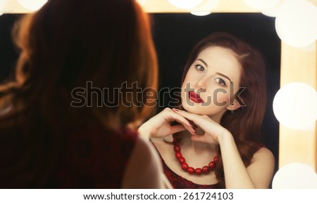 Portrait of a beautiful woman as applying makeup near a mirror.