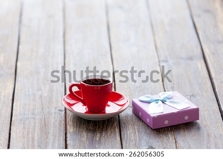 Cup of coffee and gift box on a wooden table.