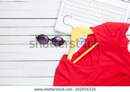 White computer with dress and sunglasses on white wooden background
