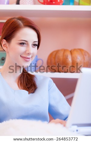 Redhead girl in blue blouse with computer sitting at home