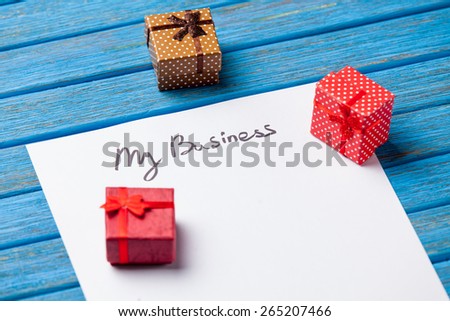 Gift boxes, books, pencil and paper with My Business words on blue background