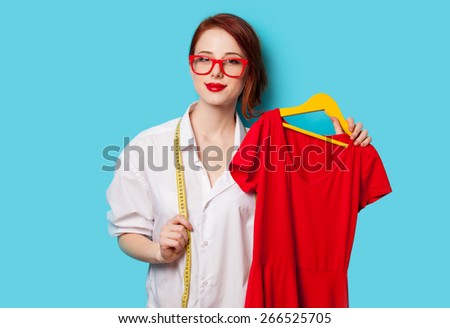 Young redhead designer with red dress on blue background