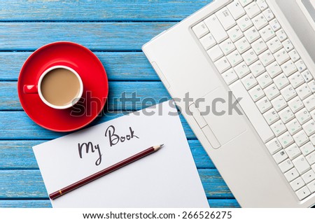 Coffee and paper with My Book inscription near notebook on blue wooden table