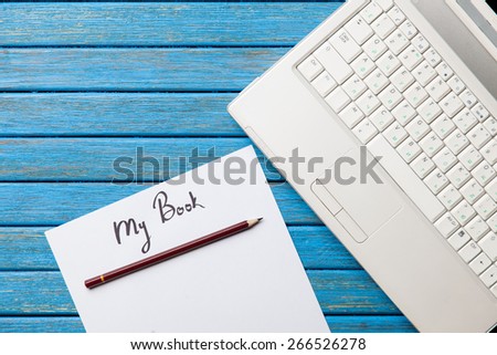 pencil and paper with My Book inscription near notebook on blue wooden table