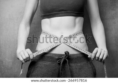 Woman showing her abs with metric after weight loss on background