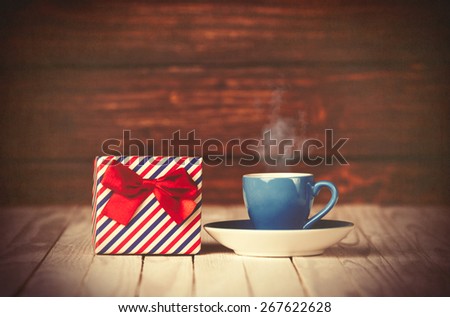 Cup of coffee and gift box on wooden table and background.