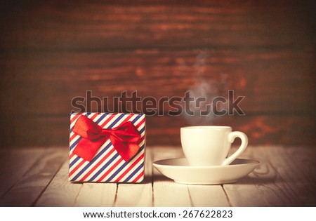 Cup of coffee and gift box on wooden table and background.