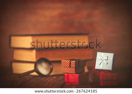 Books with loupe and gift box on wooden background.