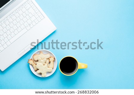 Cup of coffee and cookies with notebook on blue background