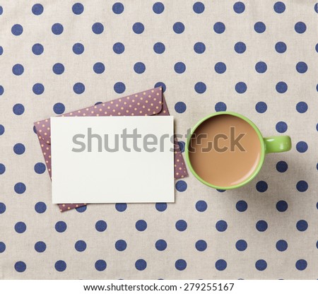 Cup of coffee and envelope on polka dot background