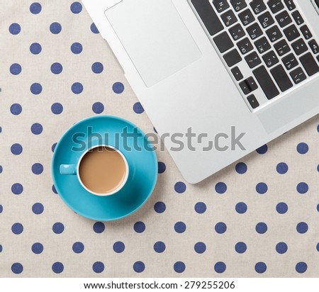 Cup of coffee and laptop computer on polka dot background