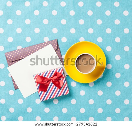 Cup of coffee and envelope with gift boxes on blue polka dot background
