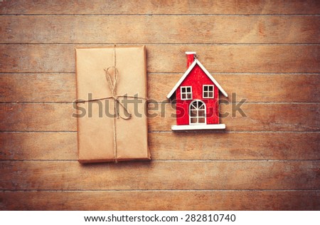 Toy house and package on wooden background. Photo in old color image style.