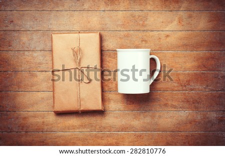 White cup and package on wooden table. Photo in old color image style.
