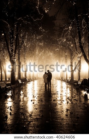 Couple walking at alley in night lights. Photo in vintage yellow style.