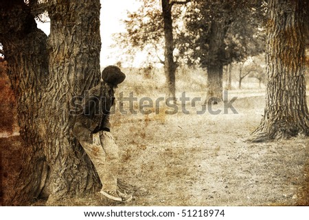 Girl hiding near tree in forest. Photo in old image style.